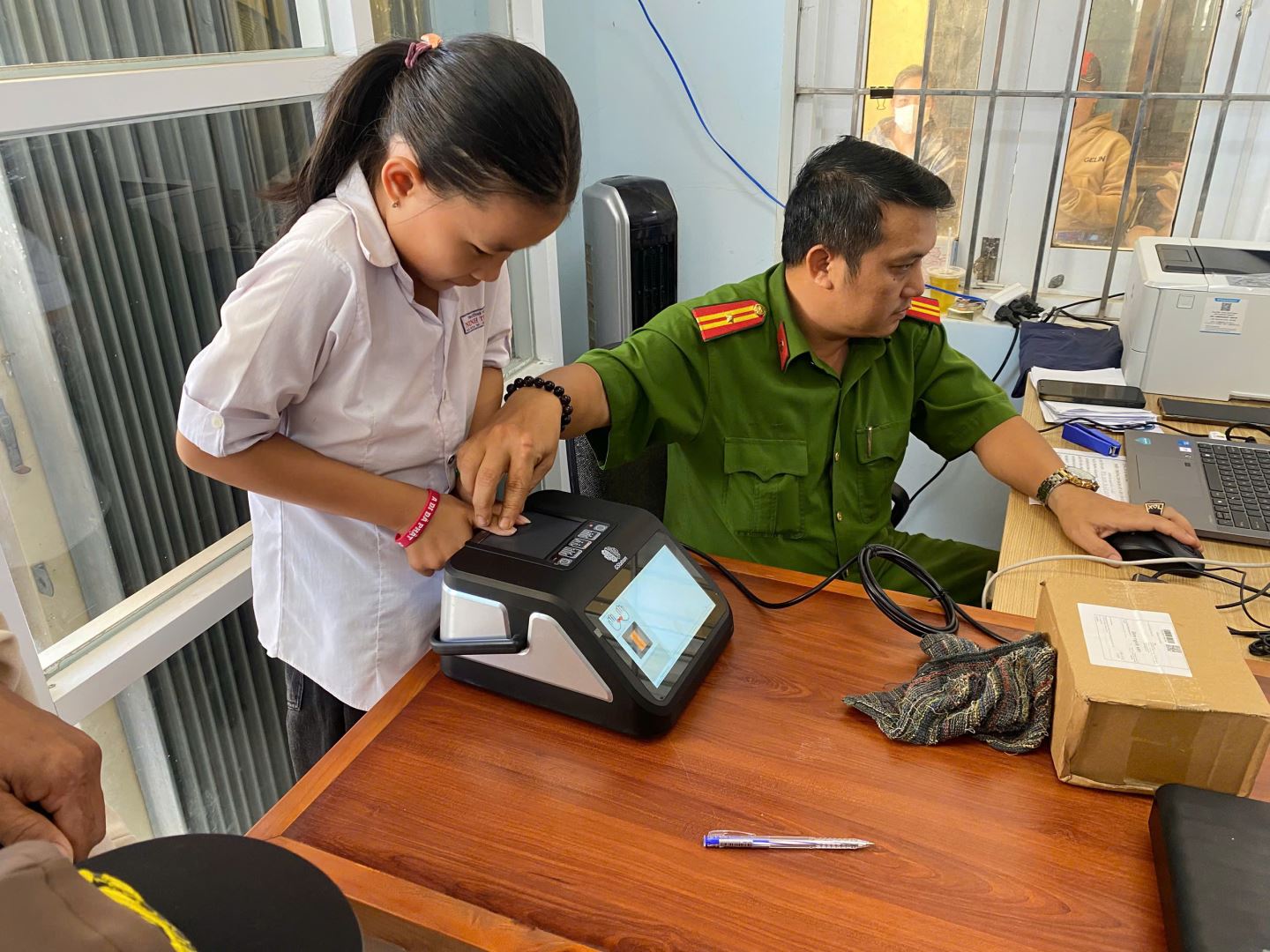 Cán bộ Công an xã thu nhận vân tay cấp Căn cước cho em học sinh