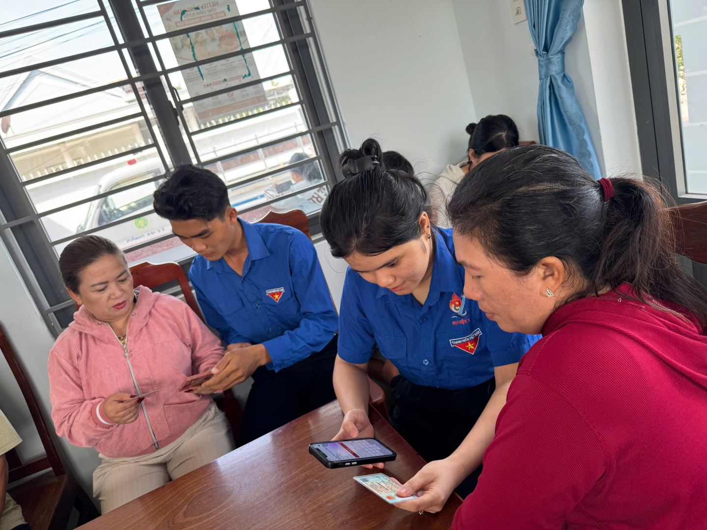 Đoàn viên thanh niên đang hướng dẫn Nhân dân kích hoạt tài khoản định danh điện tử và các tiện ích của ứng dụng VNeID